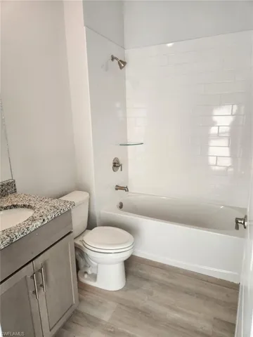 Full bathroom with tub / shower combination, vanity, and light wood-style flooring