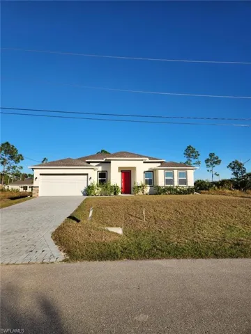 Ranch-style home with a front lawn, stucco siding, decorative driveway, and an attached garage