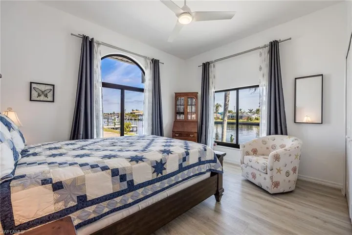Bedroom with multiple windows, a water view, access to outside, and light hardwood / wood-style floors