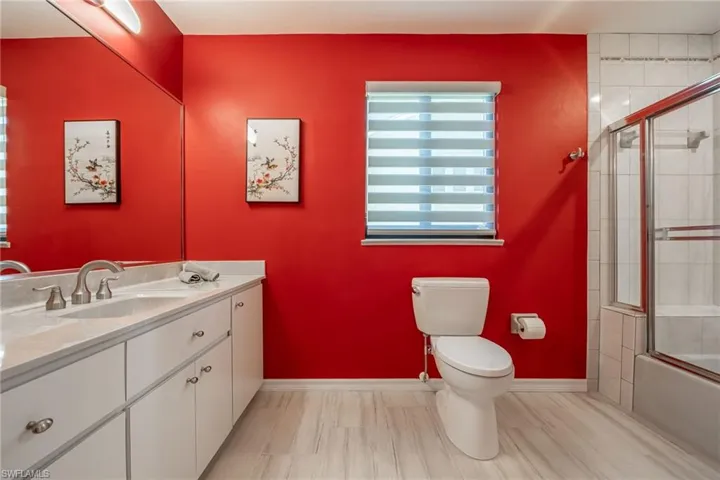 Full bathroom featuring vanity, bath / shower combo with glass door, and toilet