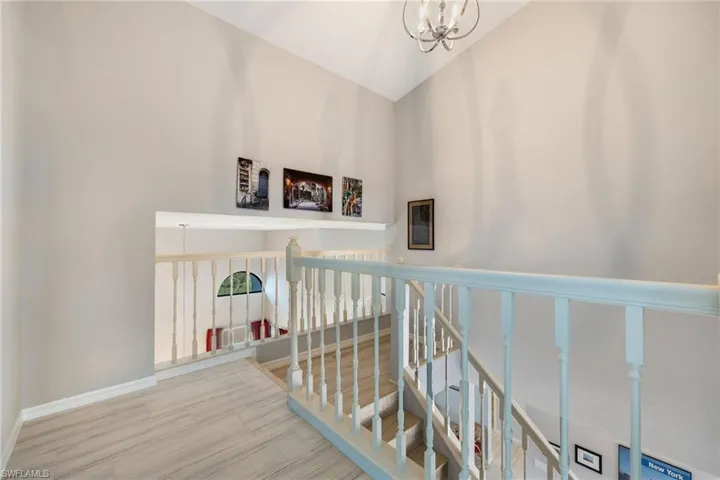Stairs featuring a notable chandelier, hardwood / wood-style flooring, and high vaulted ceiling