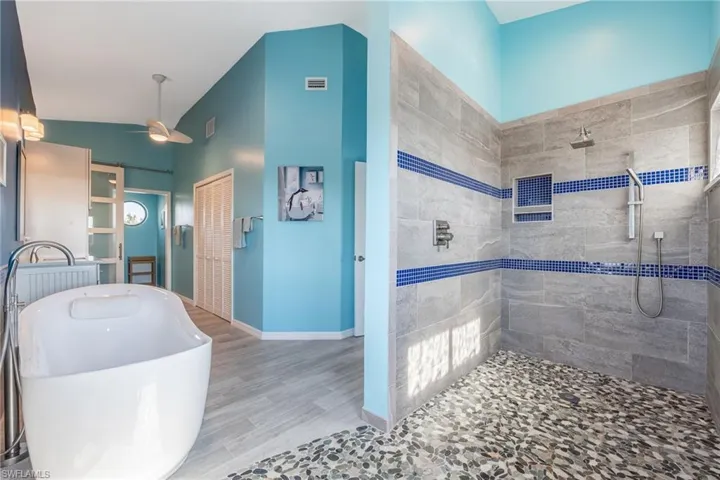Bathroom featuring ceiling fan, tiled shower, and hardwood / wood-style flooring