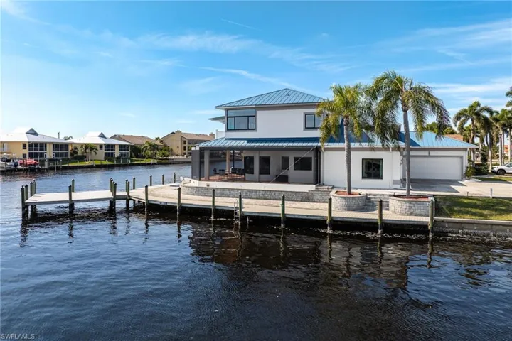 Back of property featuring a water view and a patio area