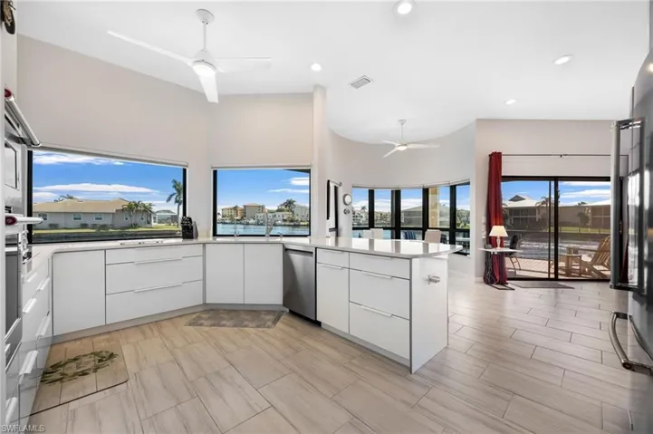 Kitchen featuring white cabinetry, stainless steel dishwasher, kitchen peninsula, and ceiling fan