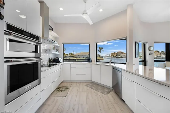 Kitchen featuring sink, a water view, appliances with stainless steel finishes, white cabinets, and backsplash