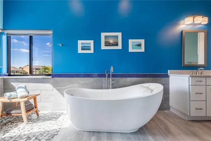 Bathroom with vanity, wood-type flooring, tile walls, and a washtub