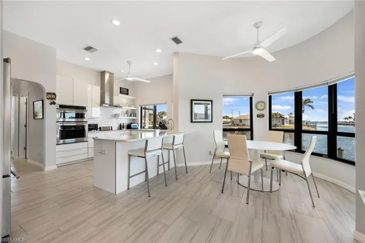 Kitchen featuring ventilation hood, white cabinets, ceiling fan, a water view, and stainless steel double oven