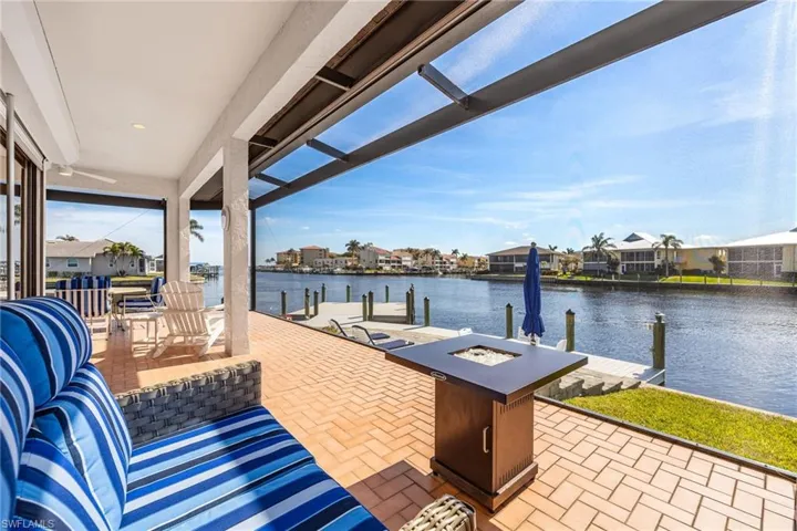 View of patio featuring a water view, an outdoor living space with a fire pit, and a boat dock