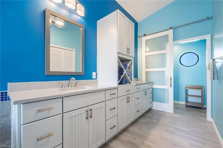 Bathroom featuring wood-type flooring, lofted ceiling, and vanity