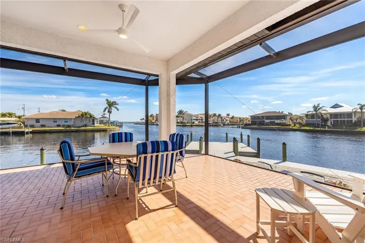 View of patio featuring a river and intersecting canal view, a boat dock, and ceiling fan
