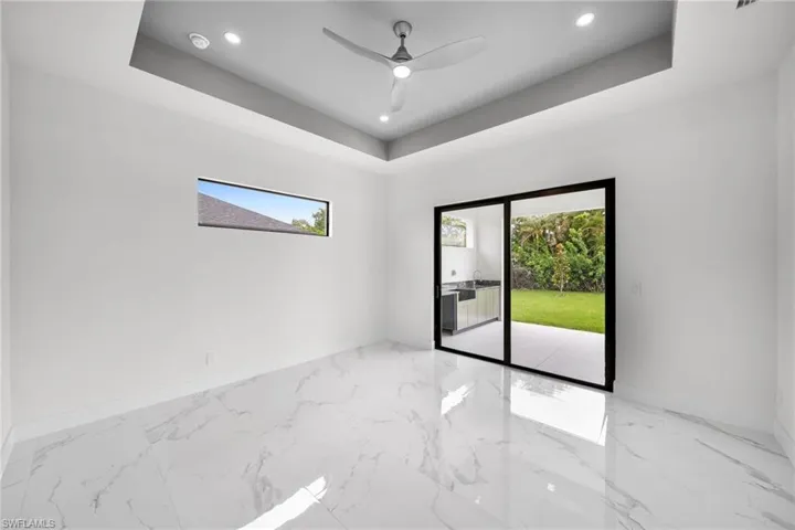 Tiled spare room with ceiling fan and a tray ceiling
