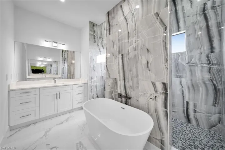 Bathroom with tile floors, tile walls, shower with separate bathtub, and vanity