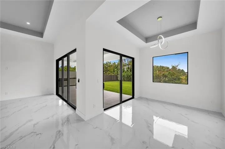 Tiled empty room with a tray ceiling and a chandelier