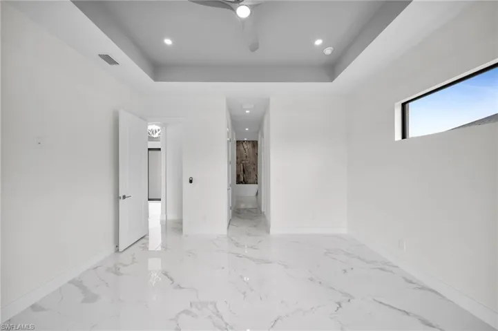 Unfurnished room featuring ceiling fan, light tile floors, and a raised ceiling