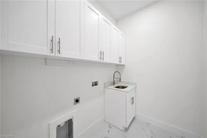 Laundry area with washer hookup, hookup for an electric dryer, light tile floors, sink, and cabinets