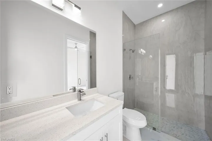Bathroom with tile flooring, walk in shower, vanity, and toilet