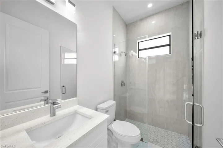 Bathroom featuring vanity, toilet, and a shower with door