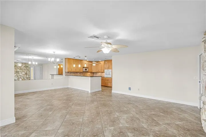 Unfurnished living room featuring a chandelier, a ceiling fan, and light tile patterned floors
