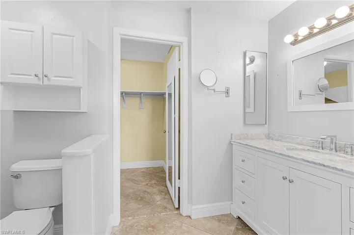 Primary Bathroom featuring a walk in closet, vanity, and light tile patterned floors