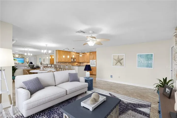 Living area featuring a chandelier, a ceiling fan, and light tile patterned flooring- Virtually Staged