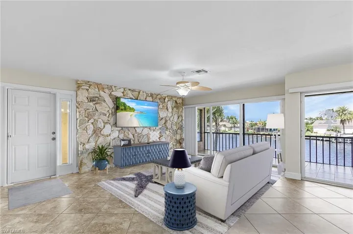 Living area with healthy amount of natural light, light tile patterned floors, and ceiling fan- Virtually Staged