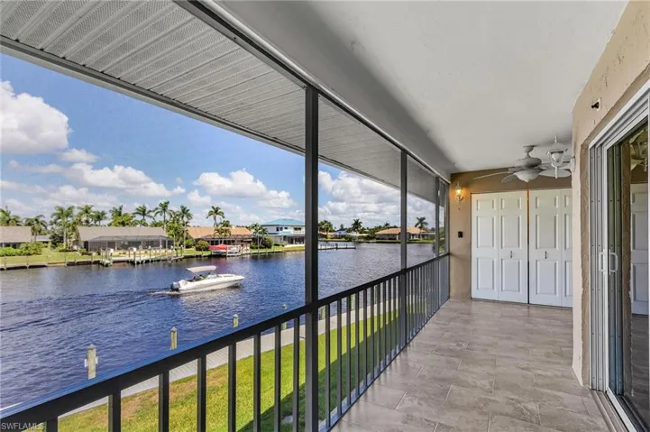 Balcony with a water view, a residential view, and ceiling fan