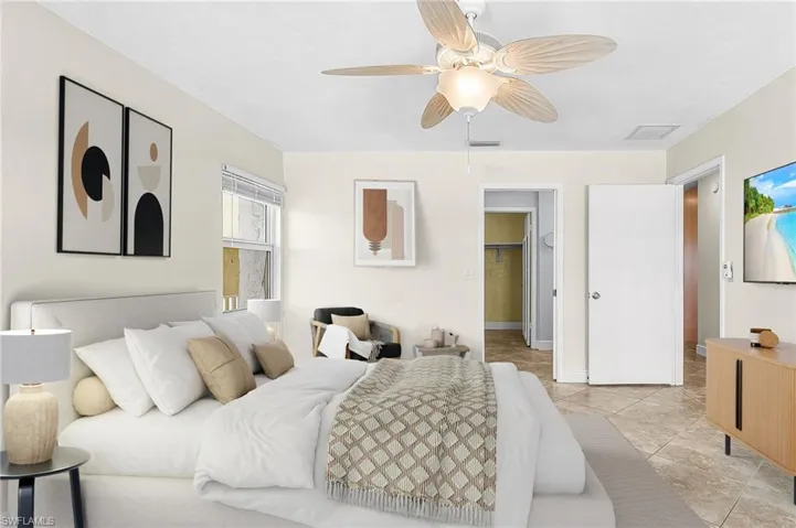 Primary Bedroom featuring a spacious closet, ceiling fan, and light tile patterned floors- Virtually Staged