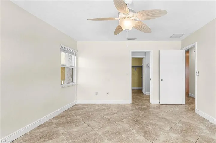 Primary Unfurnished bedroom with a spacious closet, ceiling fan, and light tile patterned floors