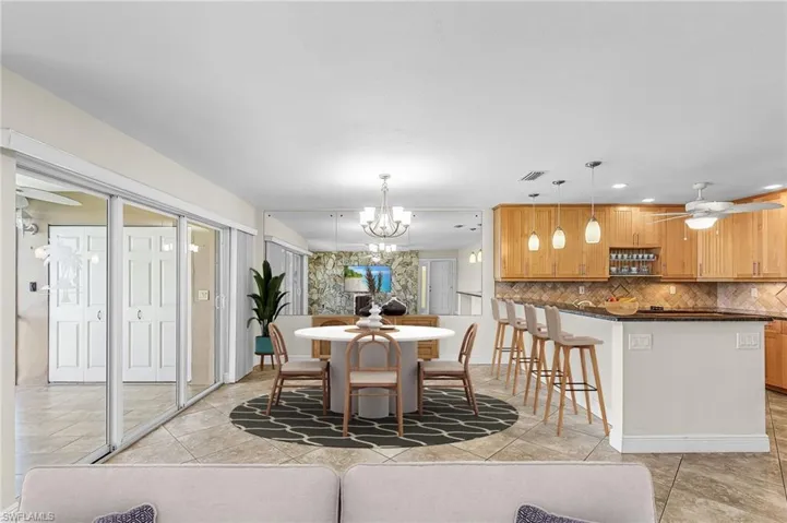 Dining space with ceiling fan, light tile patterned floors, a chandelier, and recessed lighting- Virtually Staged