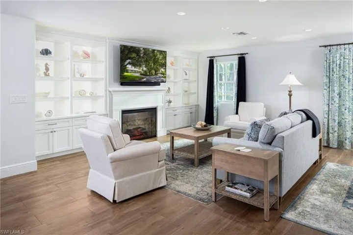 Living area with a glass covered fireplace, light wood-style floors, recessed lighting, and built in features