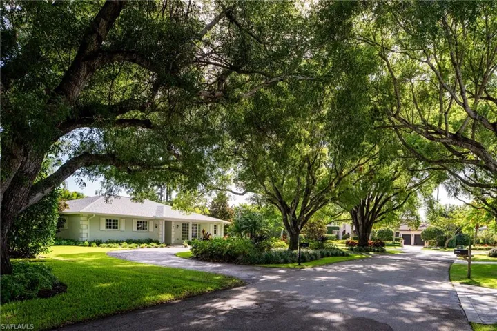View of front of house featuring a front lawn and curved driveway