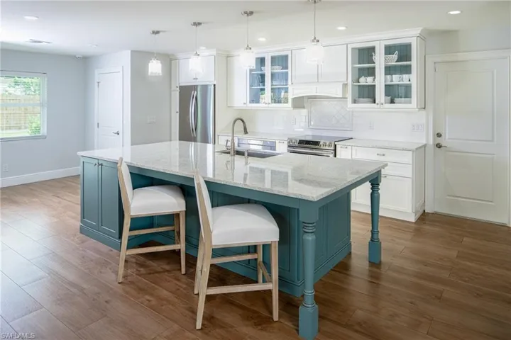 Kitchen featuring stainless steel appliances, white cabinets, a kitchen bar, decorative backsplash, and recessed lighting