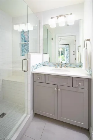 Full bathroom featuring tile patterned flooring, a shower stall, vanity, and tasteful backsplash