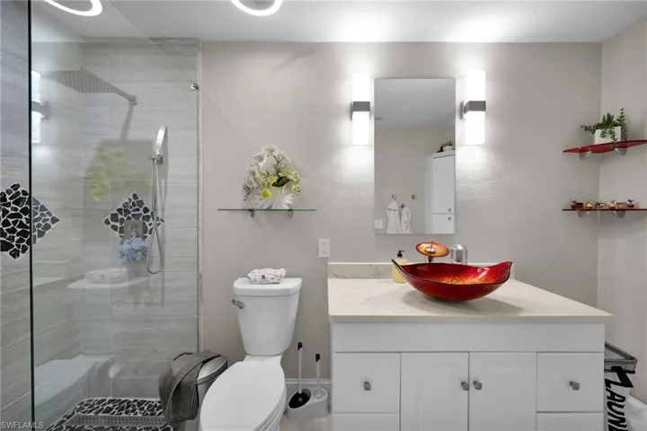 Bathroom featuring vanity, a shower with shower door, and toilet