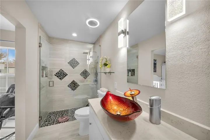 Bathroom with vanity, toilet, tile patterned floors, and a shower with door