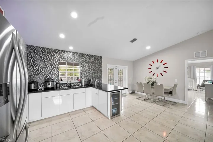Kitchen with kitchen peninsula, white cabinets, a healthy amount of sunlight, and stainless steel fridge with ice dispenser