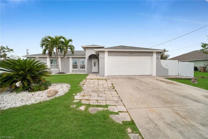View of front facade featuring a front yard and a garage