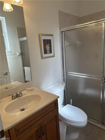 Bathroom with tile patterned flooring, vanity, a shower with shower door, and toilet