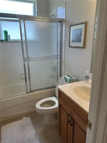Full bathroom featuring tile patterned floors, vanity, enclosed tub / shower combo, and toilet
