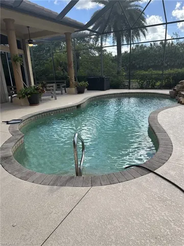 View of swimming pool with glass enclosure, ceiling fan, and a patio area