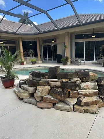 View of swimming pool featuring ceiling fan, a patio area, and glass enclosure