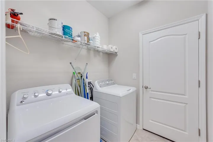 Laundry room, washer and clothes dryer, and light tile patterned flooring