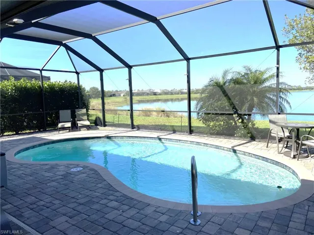 Outdoor pool featuring screen enclosure, a water view, and a large paver patio