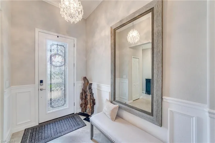Foyer featuring light tile patterned flooring, a decorative wall,  and wainscoting