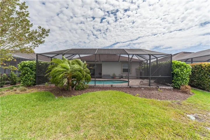 Rear view of property with screen enclosure, a lawn, a patio area, and an outdoor pool