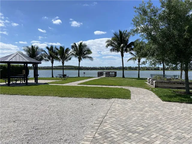 View of community featuring a garden, a water view, a lawn, and a gazebo
