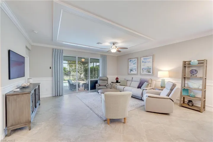 Living area with a ceiling fan, wainscoting, crown molding,