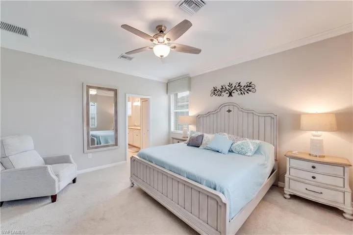 Large Primary Bedroom with light colored carpet, and crown molding