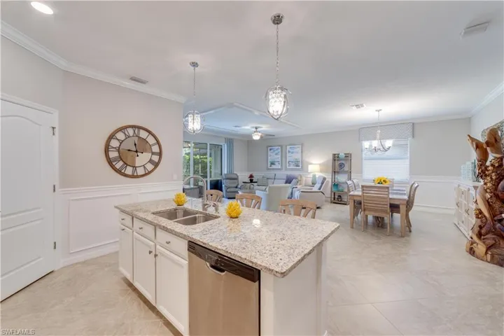 Kitchen featuring a center island with sink, stainless steel dishwasher, open floor plan, white cabinetry, and granite counter tops