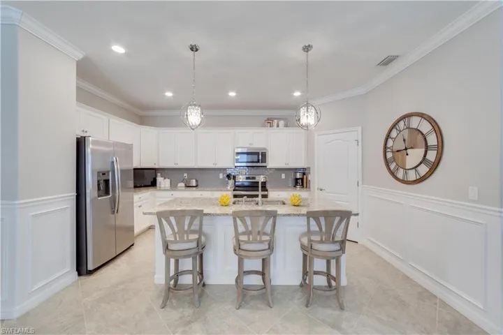 Kitchen featuring white cabinetry, stainless steel appliances and an island with sink